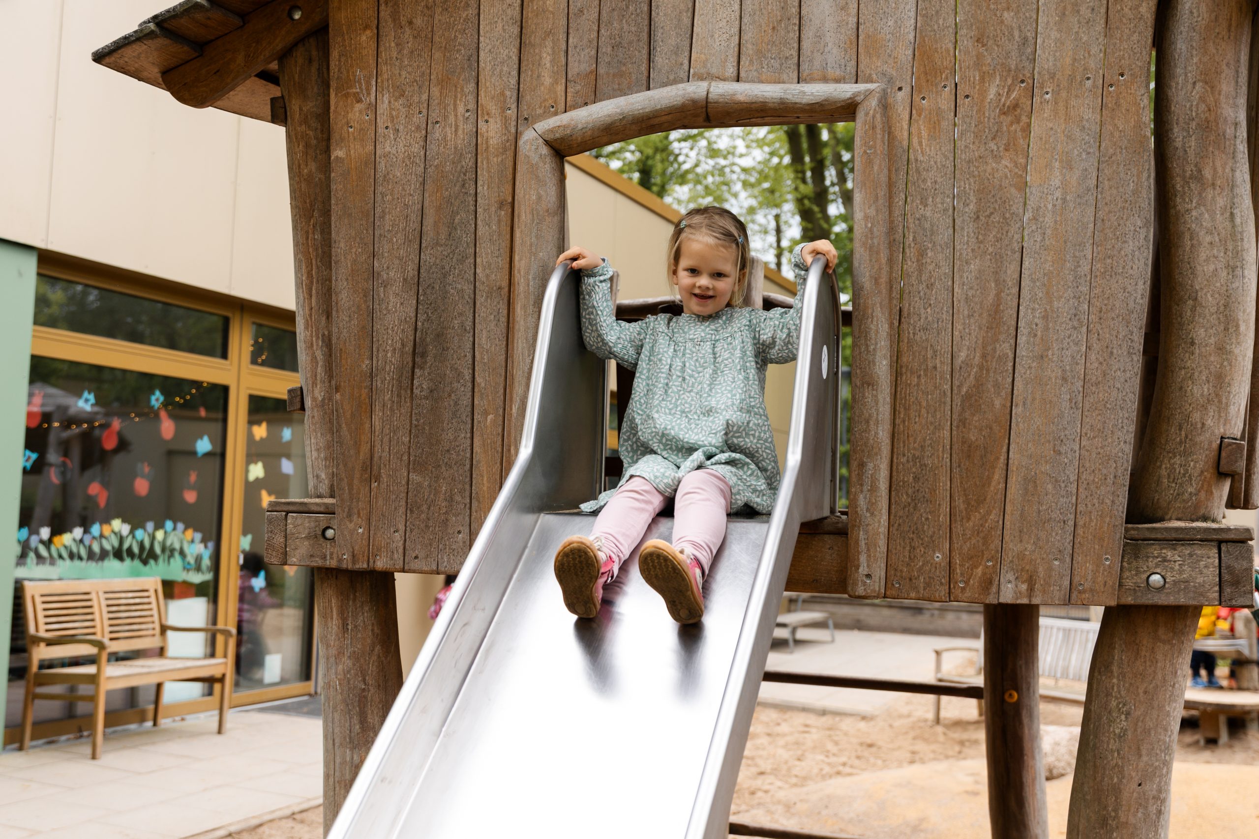Kind rutsch bei der natürlichen Kindergartenfotografie draußen auf dem Außengelände in Hamburg