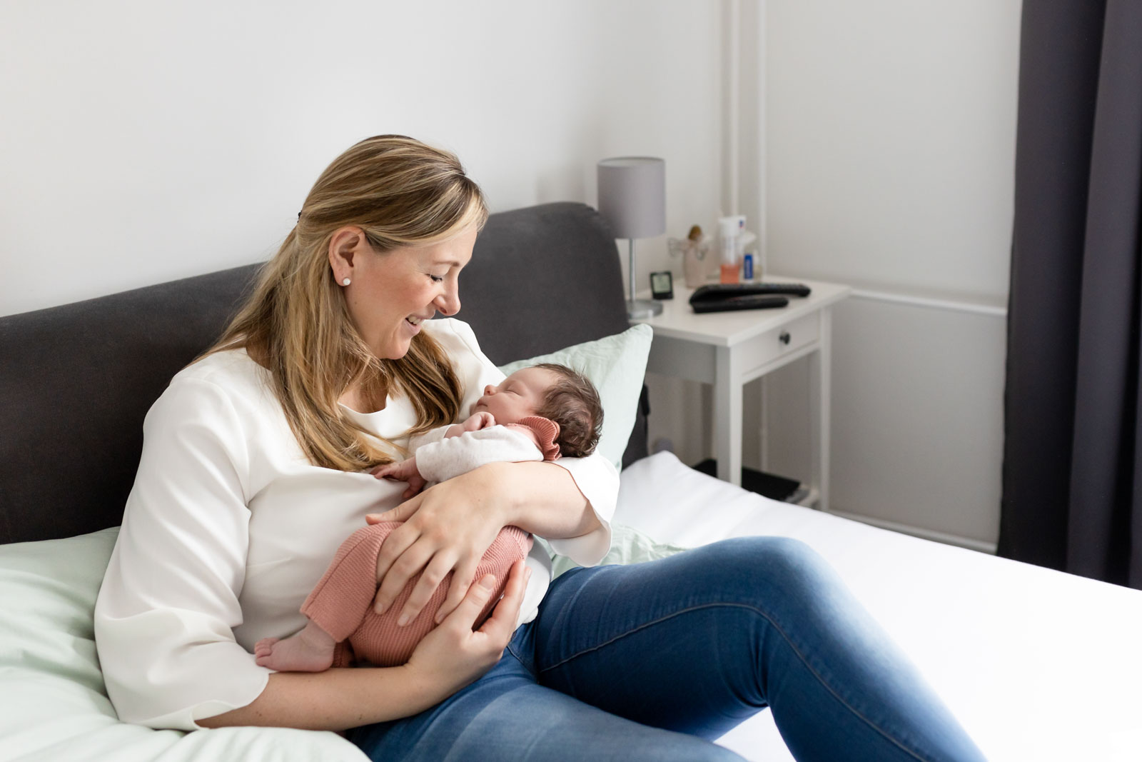 Mama und Baby kuschelnd auf dem Familienbett - Neugeborenenfotos im eigenen Zuhause in Hamburg