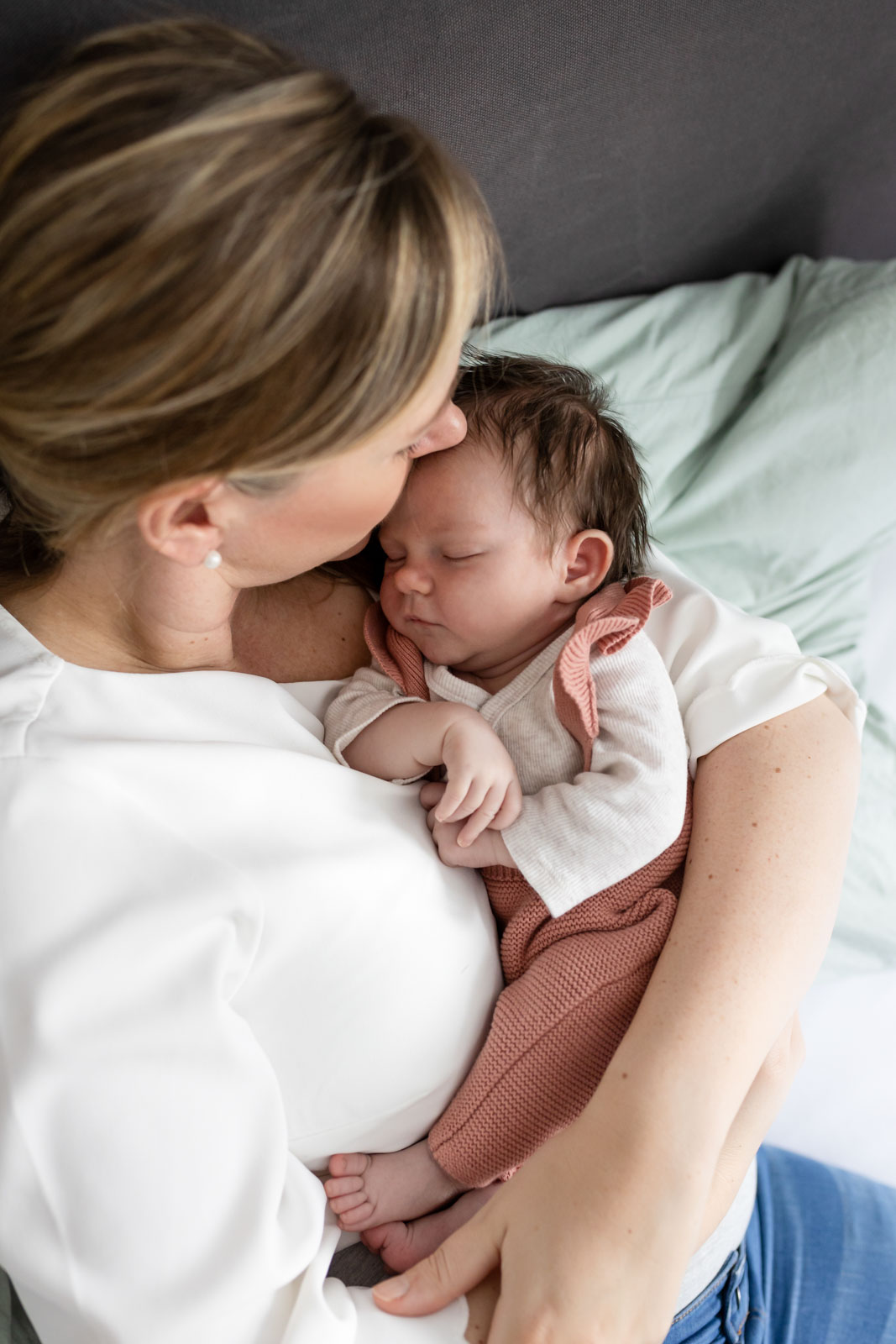 Mama und Baby kuschelnd auf dem Familienbett - Neugeborenenfotos im eigenen Zuhause in Hamburg
