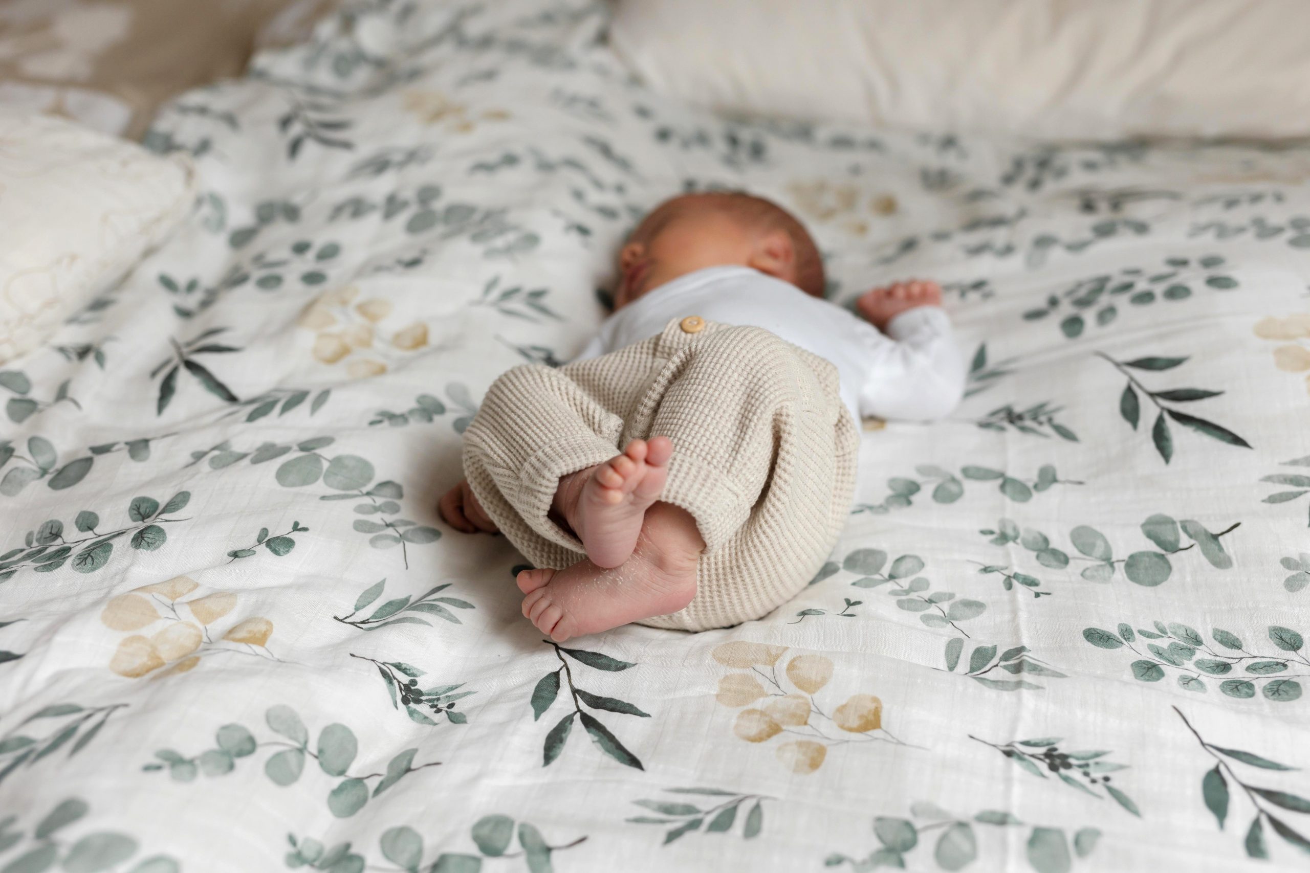 Baby liegt auf dem Familienbett - Neugeborenenbilder im eigenen Zuhause in Hamburg und Umgebung