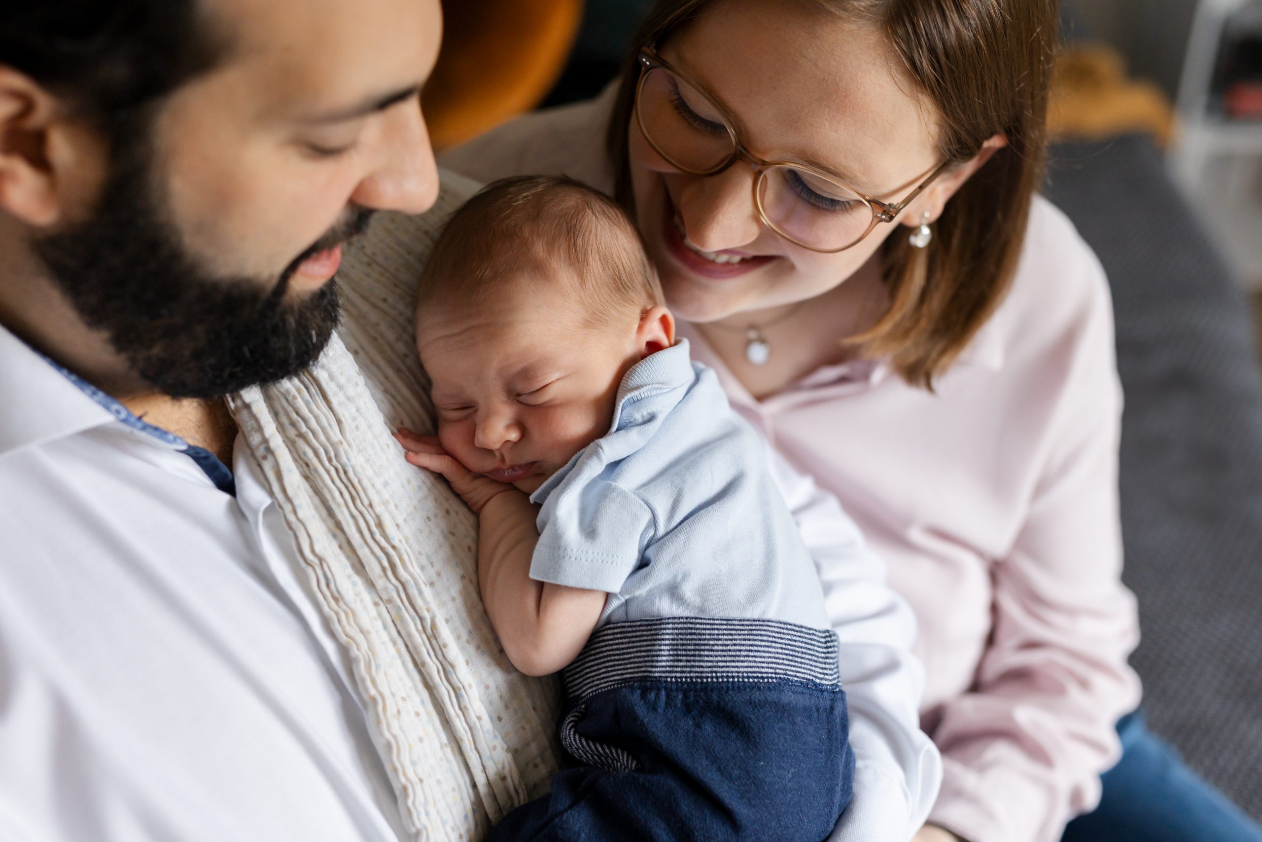 Mama und Papa kuscheln mit ihrem Baby bei professionellen Babyfotos Zuhause in Hamburg