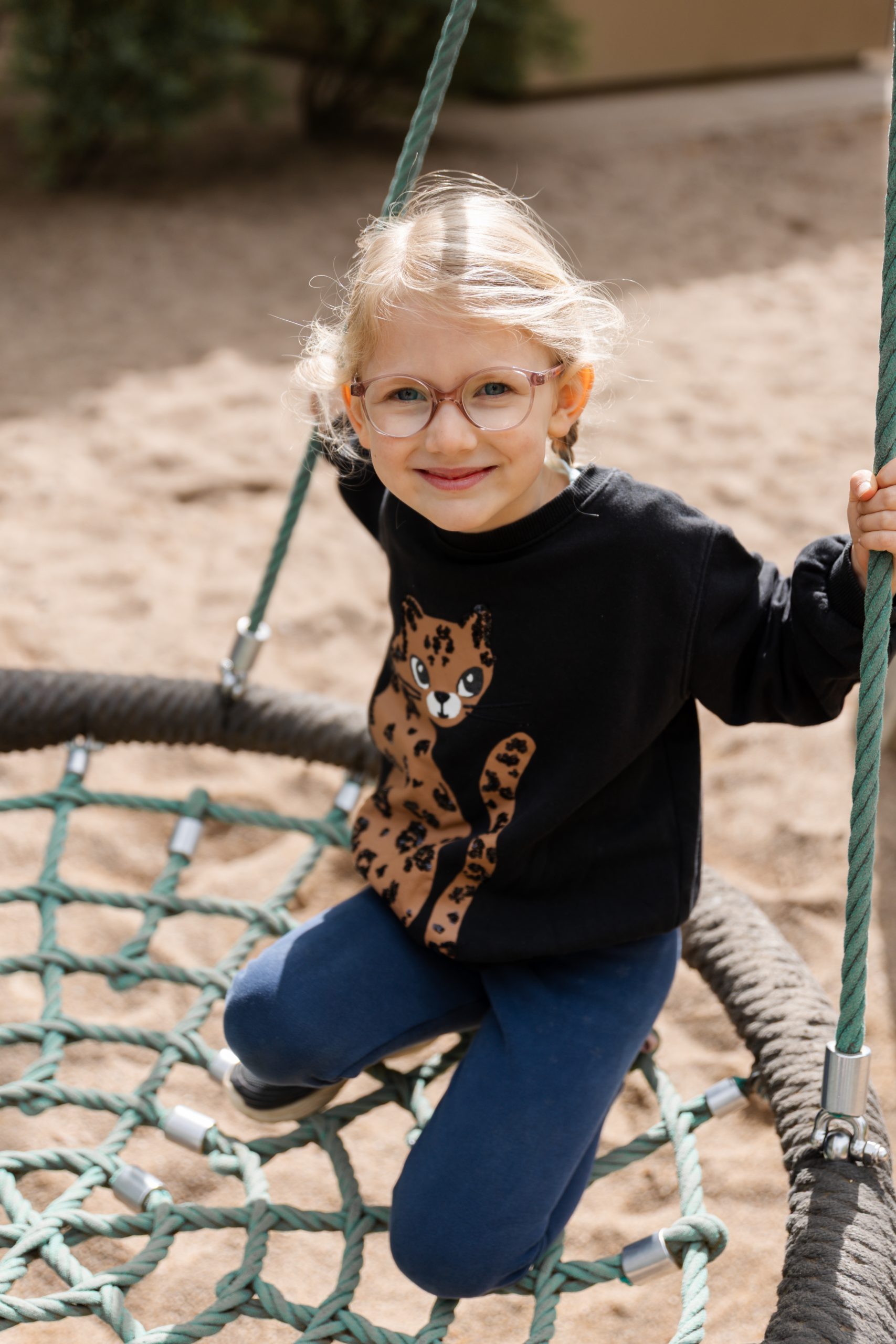 Mädchen lächelt und sitzt in der Nestschaukel - Kitafotograf Hamburg