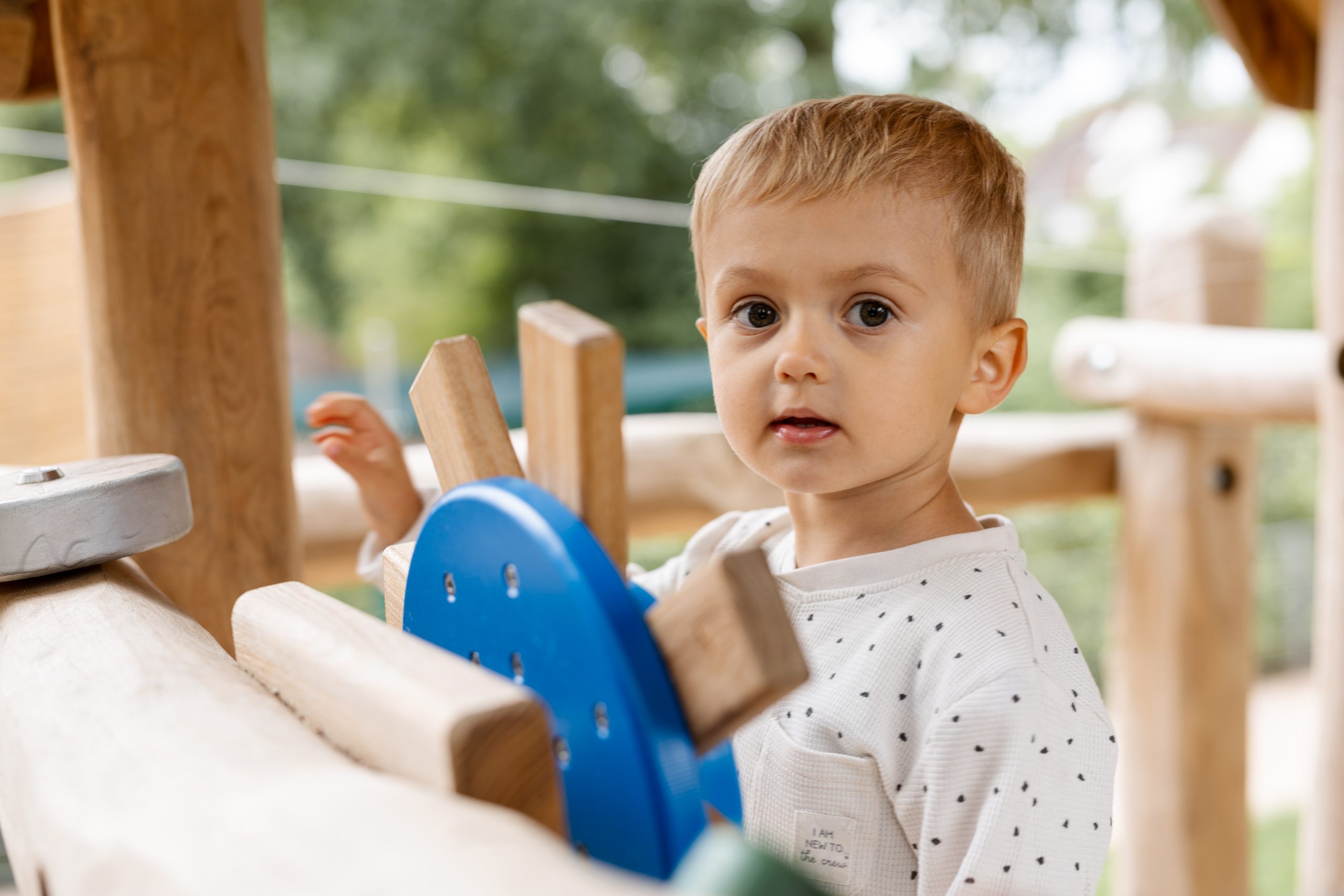 Kind rutsch bei der natürlichen Kindergartenfotografie draußen auf dem Außengelände in Hamburg